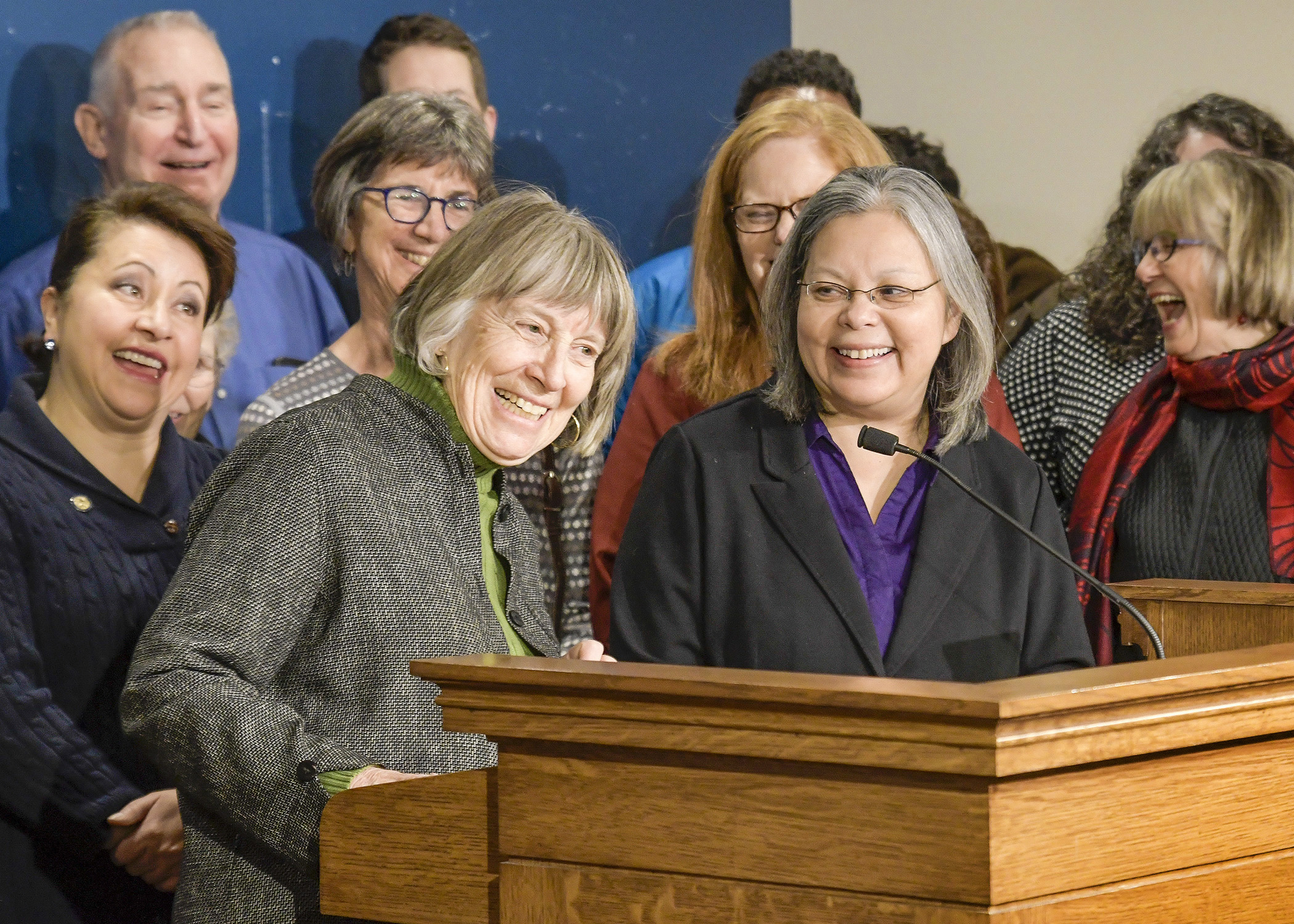 Flanked by family, friends, and colleagues during a joint news conference, Reps. Karen Clark, center left, and Susan Allen, center right, announced Friday they will not seek re-election. Photo by Andrew VonBank